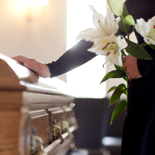 woman-with-lily-flowers-and-coffin-at-funeral