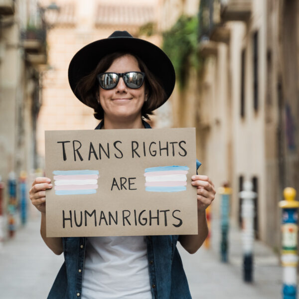 Transgender hipster woman fighting for transsexual human rights at gay pride holding banner